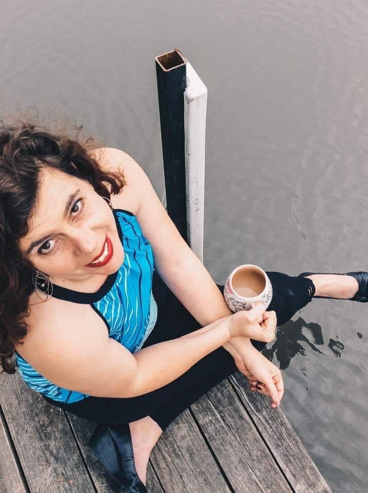 Tiffini Wright sitting on a dock at the Lake of the Ozarks, coffee in hand